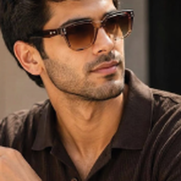 Man with dark hair and stubble wearing brown sunglasses, looking to the right.